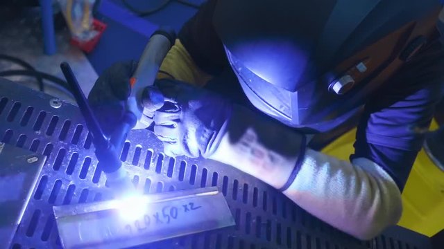 Welder is going welding of the metal detail. Sparks are flying in different directions. Slow motion, high speed camera, 250fps
