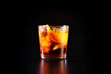 Glass of alcohol on a black table in the bar. Lonely scottish glass of whiskey with ice.