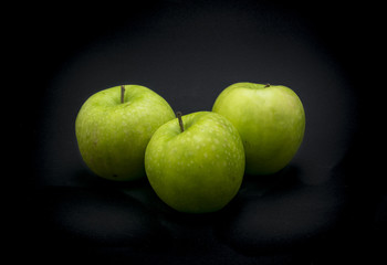 Green apples on black background.