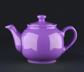 Violet ceramic teapot isolated on black background