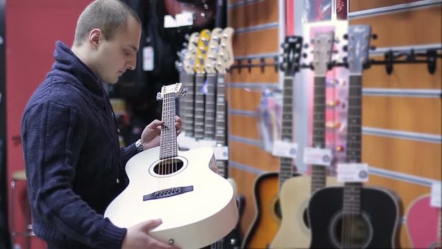 Shop musical instruments. Young Man chooses a guitar