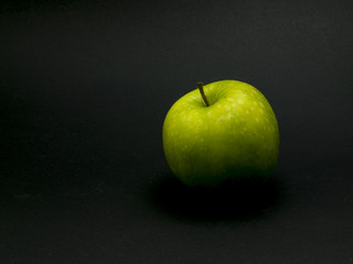 Single green apple on black background.