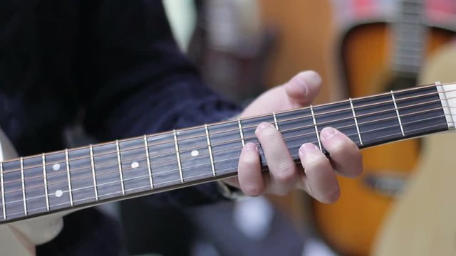 Shop musical instruments. Close up of a Young Man chooses a guitar