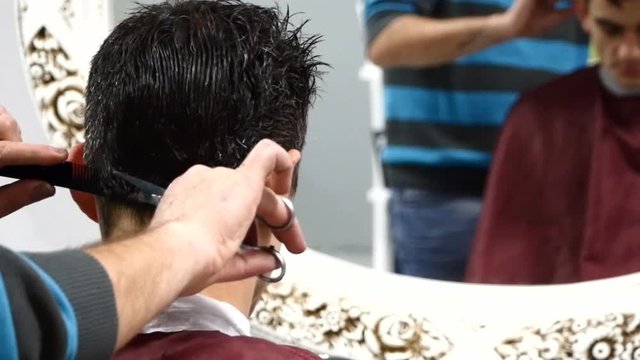 The man is standing and making haircut for a man.