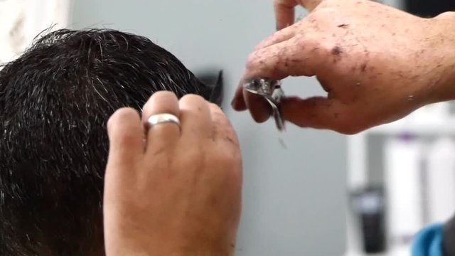 The man is standing and making haircut for a man.