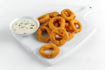 Fried Breaded Onion Rings with sauce. on white wooden board, background.