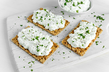 Homemade Crispbread toast with Cottage Cheese and parsley on white wooden board.