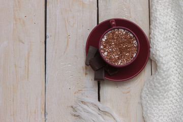 Milk chocolate in a cup on a saucer on a wooden background.