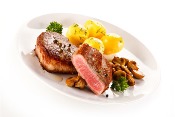 Grilled steaks, boiled potatoes and vegetable salad on white background 