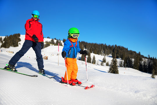 Happy little boy learning skiing with his father
