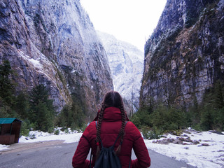 Traveler in the mountains, girl in jacket stands on the road. Mountain gorge, beautiful Northern landscape