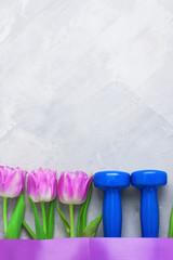Spring flatlay sports composition with blue dumbbells and purple