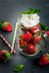 Concept of summer strawberry smoothie or drink: all the necessary ingredients for a cocktail in a mason jar. With straws on a table nearby. On the gray stone or concrete background. Copy space