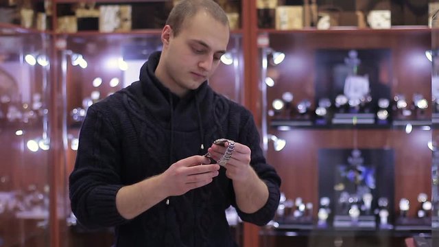 Young Man chooses wrist watch in the watch store