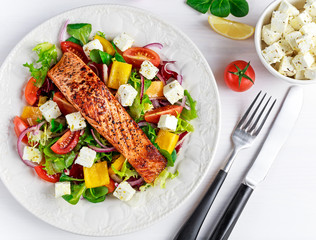 Fried Salmon steak with fresh vegetables salad, feta cheese. concept healthy food.