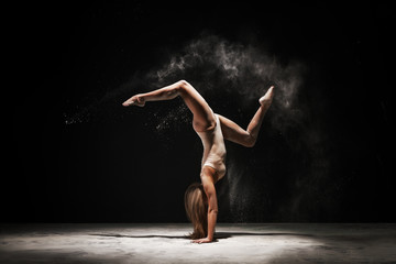 Obraz na płótnie Canvas Slender blonde dancing in white dust studio shot