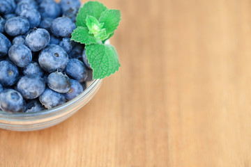 Blueberries in glass bowl background on wooden deck
