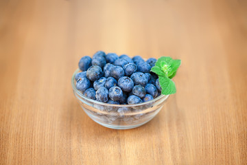 Blueberries in glass bowl on wooden deck middle