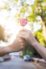 hands holding red lollipop together on circle bokeh background