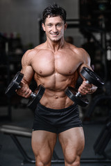 Fototapeta premium Handsome bodybuilder training in the gym sexy man lift dumbbells