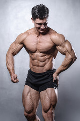 beautiful fitness male model posing in studio on white grey back