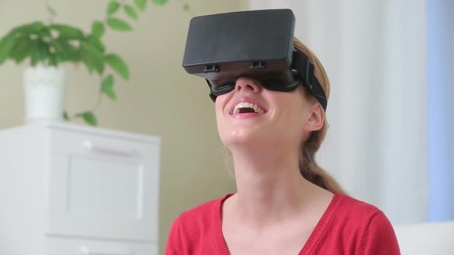 Virtual reality mask. Attractive young woman having fun uses head-mounted display in the interior.