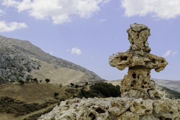 Christian stone cross on a background of cloudy sky and high mountains