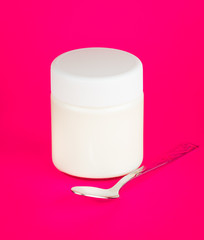 Jar with yogurt isolated on pink background.