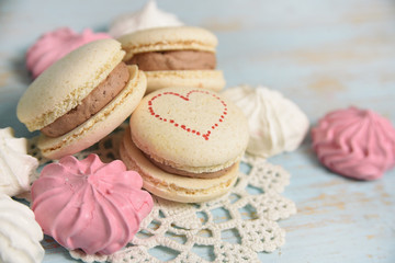 Macaroons and meringues on blue wooden background. french sweets.   