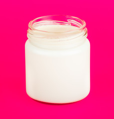 Jar with yogurt isolated on pink background.