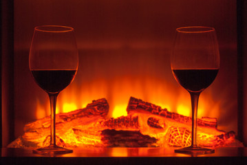 Two glasses of wine next to the fireplace.