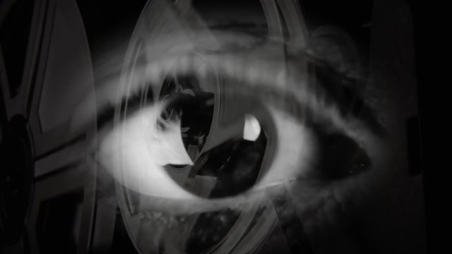 Double exposure: a big sexy eye over the moving reels of a working super-8 mm film projector.

