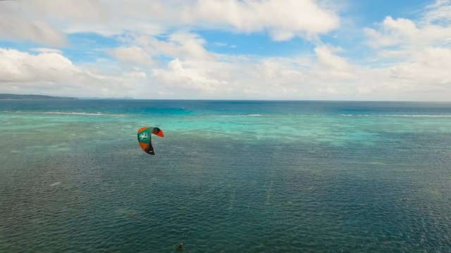 Kitesurfing on tropical island. Aerial view:kitesurfer sea rider rides at high speed through the waves. Kite surfing on a sunny day on a tropical island.Travel concept. Philippines, Boracay. 4K video