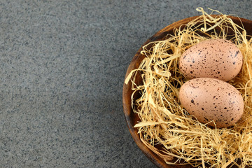 Obraz premium Two quail easter eggs on wooden plate with hay.