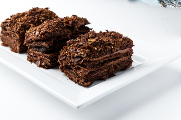 French Chocolate Napoleon cake of puff pastry with sour cream on a white plate close-up. Nutritious dessert. Selected Focus
