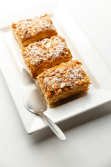 French Napoleon Cake of puff pastry with sour cream on a white plate close-up. Nutritious dessert. Selected Focus