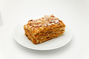 French Napoleon Cake of puff pastry with sour cream on a white plate close-up. Nutritious dessert. Selected Focus