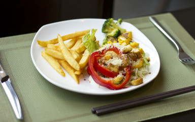 Tasty and nutritious lunch. French fries with vegetables and cheese. Food on a white plate. Beautifully decorated lunch
