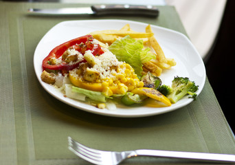 Tasty and nutritious lunch. French fries with vegetables and cheese. Food on a white plate. Beautifully decorated lunch
