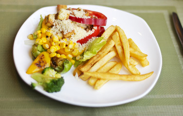 Tasty and nutritious lunch. French fries with vegetables and cheese. Food on a white plate. Beautifully decorated lunch
