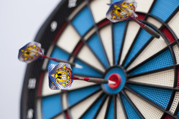 Dartboard with three darts, one hit bullseye with some selective focus