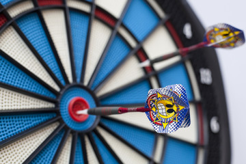 Dart with a grinning emoticon hit bullseye with selective focus on the emoticon