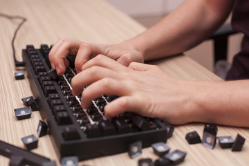 Fototapeta na wymiar Man breaks a mechanical computer keyboard by typing angrily