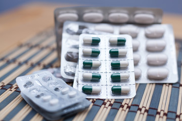 Various pills and capsules in blister packagings piled up on a table