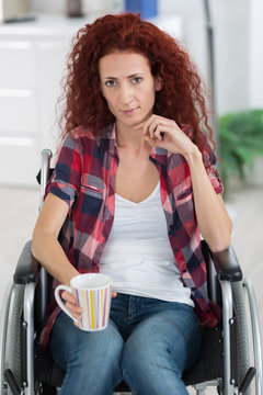 cheerful disabled woman holding hot coffee cup at home