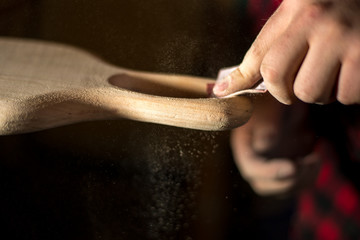 Hands manual sanding a wood handle