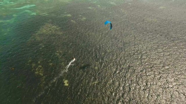 Kitesurfing on tropical island. Aerial view:kitesurfer sea rider rides at high speed through the waves. Kite surfing on a sunny day on a tropical island.Travel concept. Philippines, Boracay. 4K video