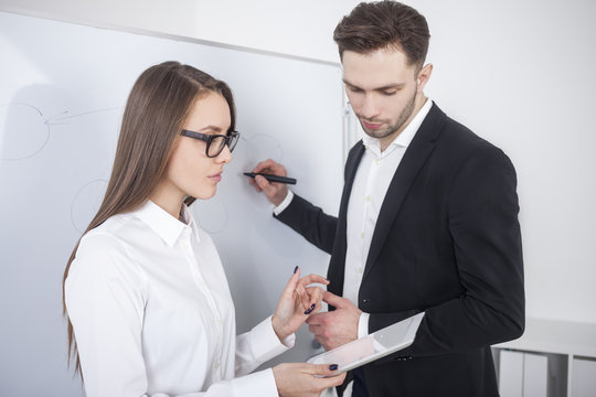 Man writing, woman holding tablet computer