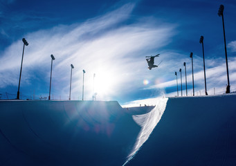 Skier doing an inverted trick in winter snow halfpipe