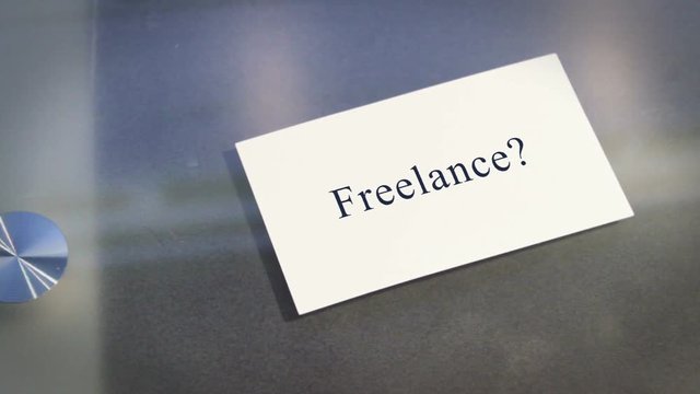 Hand puts business card on table with text Freelance